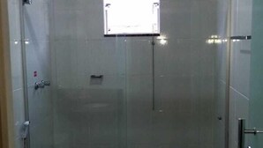 A modern bathroom with a glass shower enclosure, a toilet, and a sink with a granite countertop.