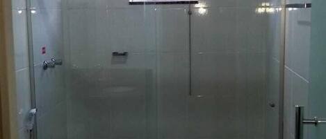 A modern bathroom with a glass shower enclosure, a toilet, and a sink with a granite countertop.