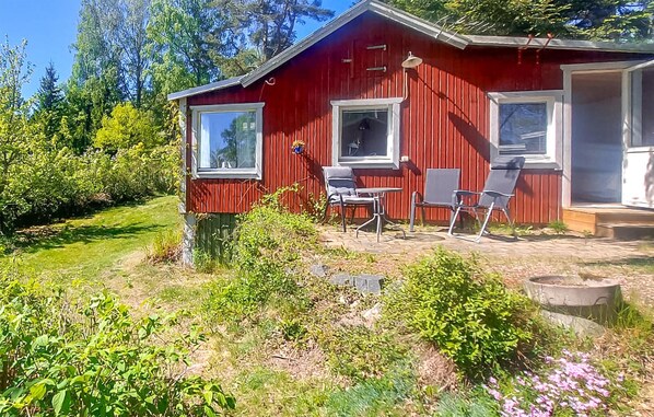 Cozy cabin with a patio and garden, featuring a door, windows, and outdoor seating area.