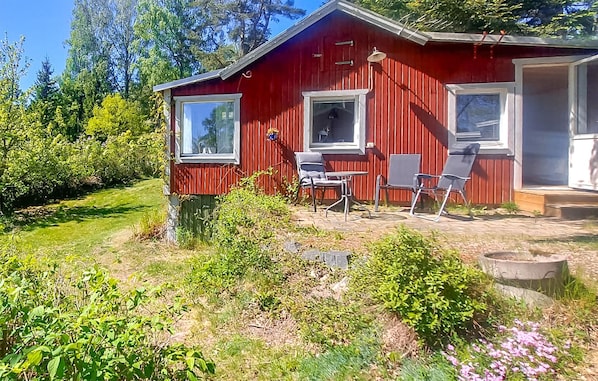 Cozy cabin with a patio and garden, featuring a door, windows, and outdoor seating area.