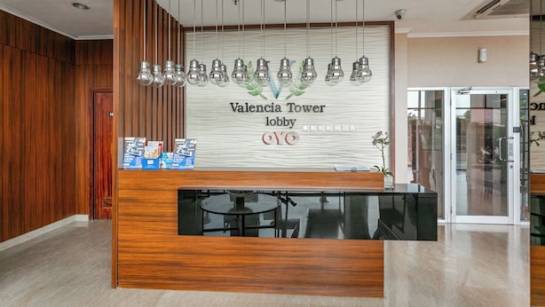 Ein Empfangsschalter mit Holzoptik, einer Arbeitsplatte aus Glas und einem Schild mit der Aufschrift 'Valencia Tower lobby'.