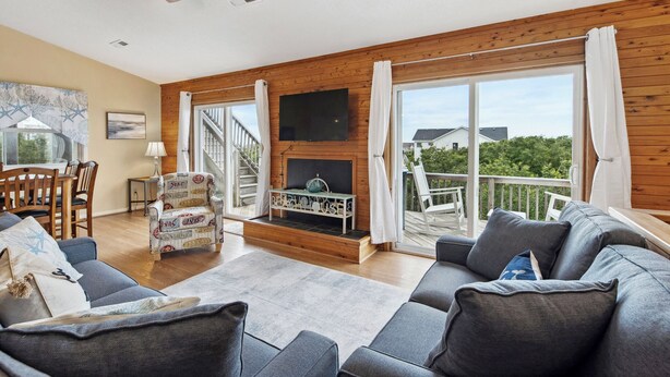 Ein geräumiges Wohnzimmer mit Kamin, großen Fenstern und einem Balkon.