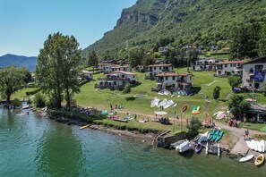 Un borgo affacciato su un lago, con case, barche e montagne sullo sfondo.