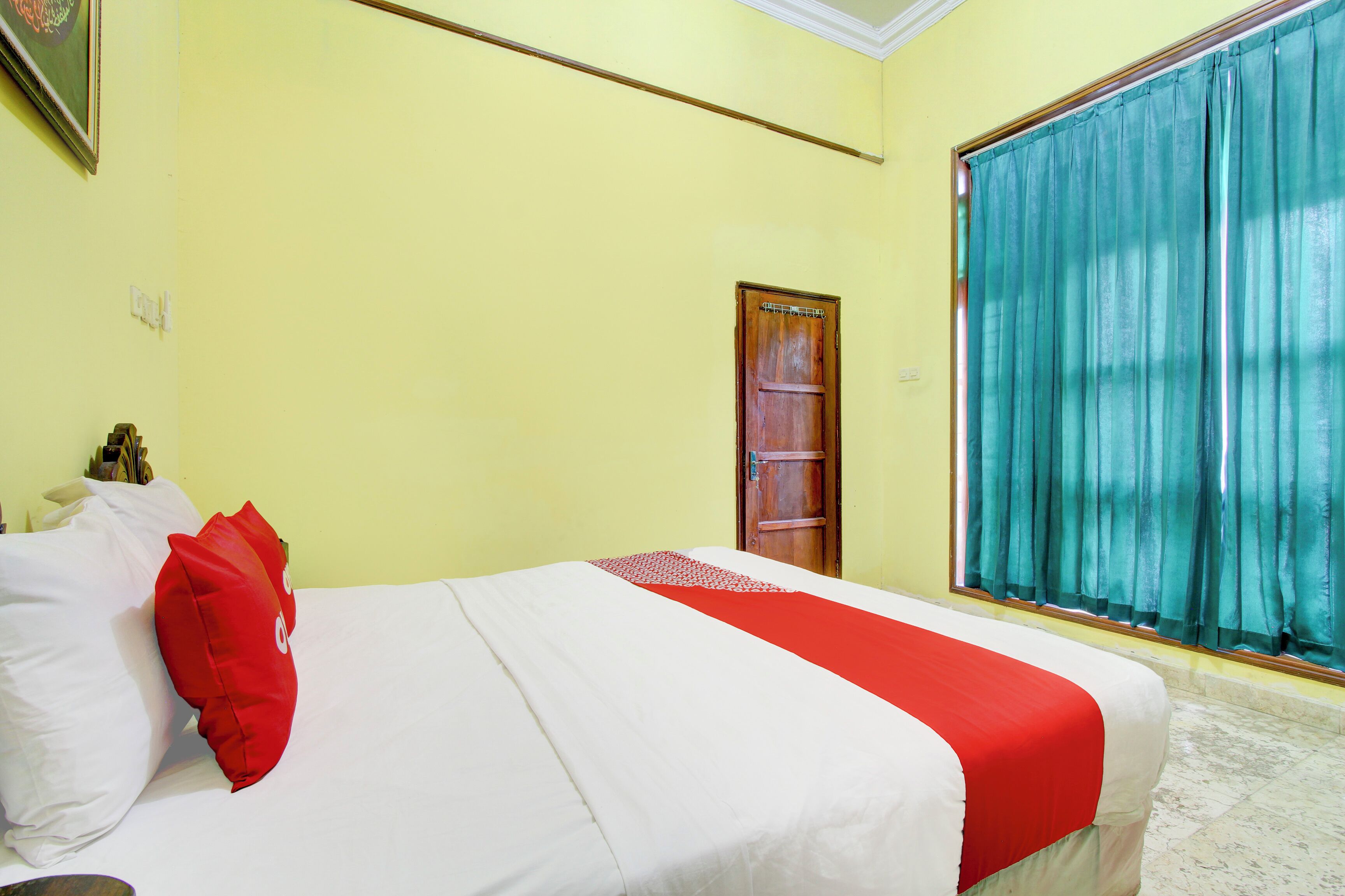A room with a bed, a door, and a window with curtains.