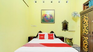 A hotel room with a bed, a wall-mounted artwork, a bedside table, and a wardrobe. - Hotel O Homestay Ndalem Kademangan (Ngaglik)