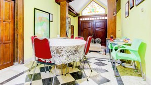 A dining area with a round table, red and green chairs, and a lace tablecloth. - Hotel O Homestay Ndalem Kademangan (Ngaglik)