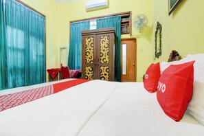 A hotel room with a bed, curtains, a wardrobe, a fan, and a door. - Hotel O Homestay Ndalem Kademangan (Ngaglik)