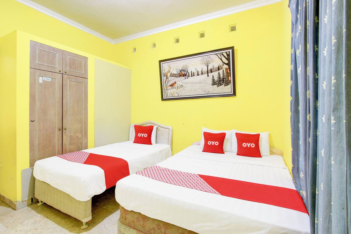 A hotel room with two beds, each with a red and white bedspread and pillows labeled "OYO".