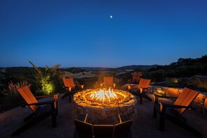 Relax by the fire pit in a serene outdoor setting surrounded by Adirondack chairs.