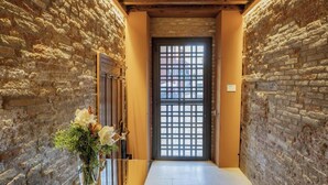 A narrow hallway with exposed brick walls and a wooden door with a grid pattern.