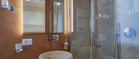 A modern bathroom with a round sink, a glass shower enclosure, and a mirror above the sink.
