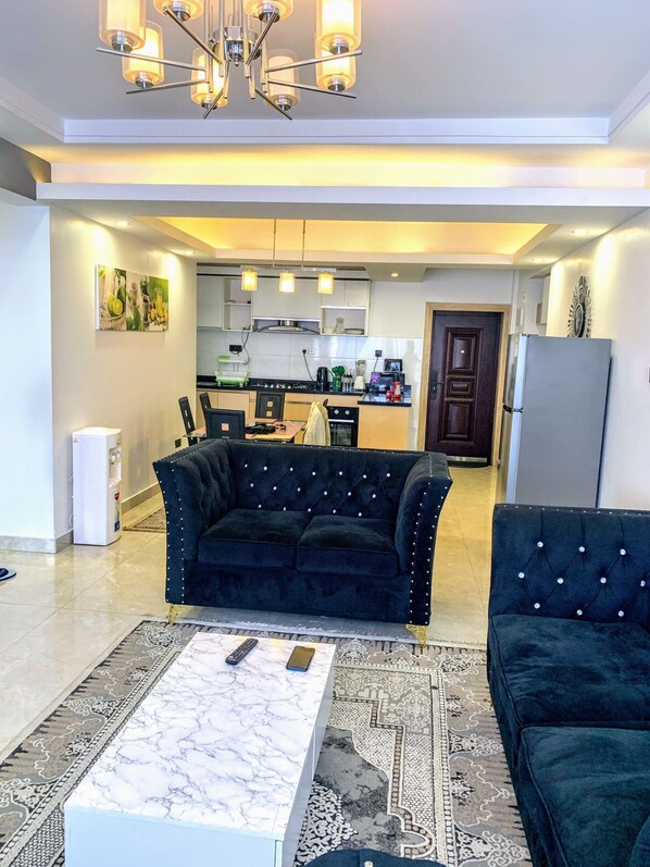 A modern living room with a dark blue sofa, a marble coffee table, and a patterned rug. - Urban Oasis Apartments Lavington (Nairobi)