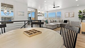 Una sala de estar moderna con una mesa de comedor redonda, un juego de sofá y vistas al exterior.