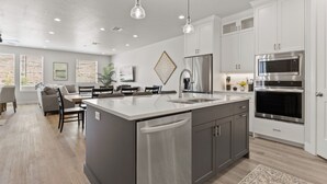 Una cocina moderna con armarios blancos, electrodomésticos de acero inoxidable y una isla central con un lavamanos.