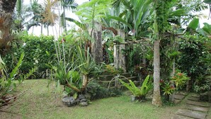 A garden with a stone pathway, lush greenery, and a variety of plants. - Capital O 94012 Dewa Jati House (Sebatu)