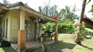 A house with a porch, a small garden, and a palm tree. - Capital O 94012 Dewa Jati House (Sebatu)