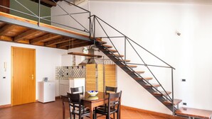 Ein Essbereich mit Tisch und Stühlen, eine Treppe und eine Küche im Hintergrund.