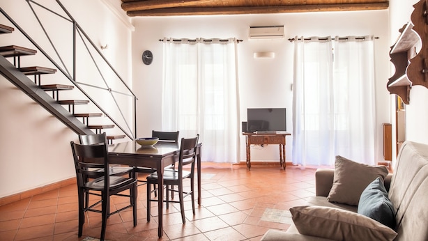 Ein Wohnzimmer mit Treppe, Essbereich und Fernseher.