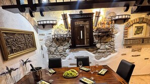 A dining area with a wooden table set for four, surrounded by stone walls and a rustic interior. - Old house Njivice (Omisalj)
