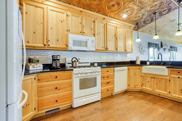 A kitchen with wooden cabinets, a microwave, stove, and a sink. - Lakefront Vacation Rental ~ 10 Mi to Shipshewana! (Howe)