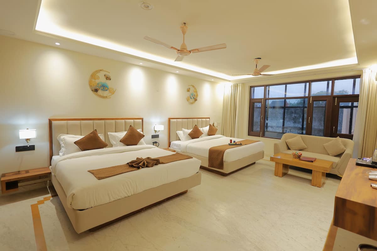 A hotel room with two beds, a sofa, a coffee table, and a desk.