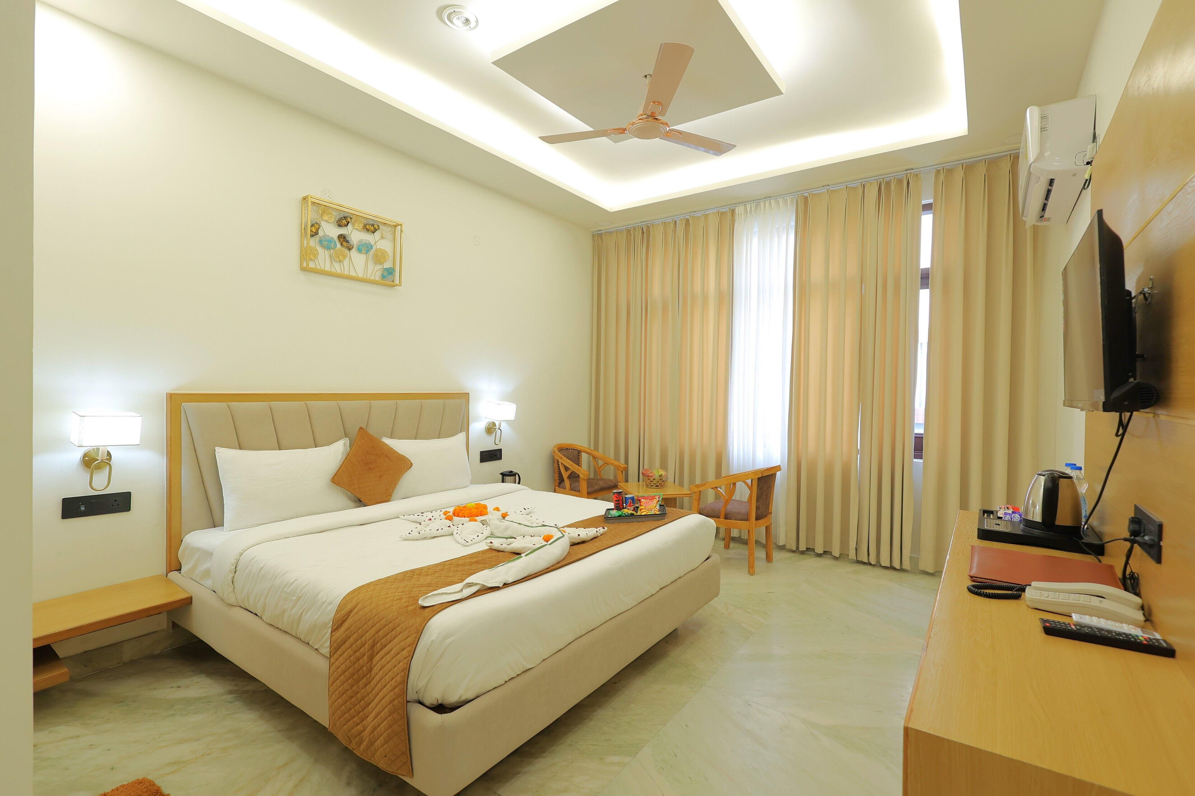 Une chambre d’hôtel équipée d’un lit, d’un bureau, d’une chaise, d’un ventilateur de plafond et d’un téléviseur.