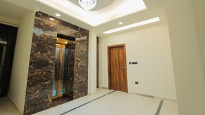 A modern interior with a marble wall, a wooden door, and a ceiling light fixture. - Shree radha heritage (Haridwar)