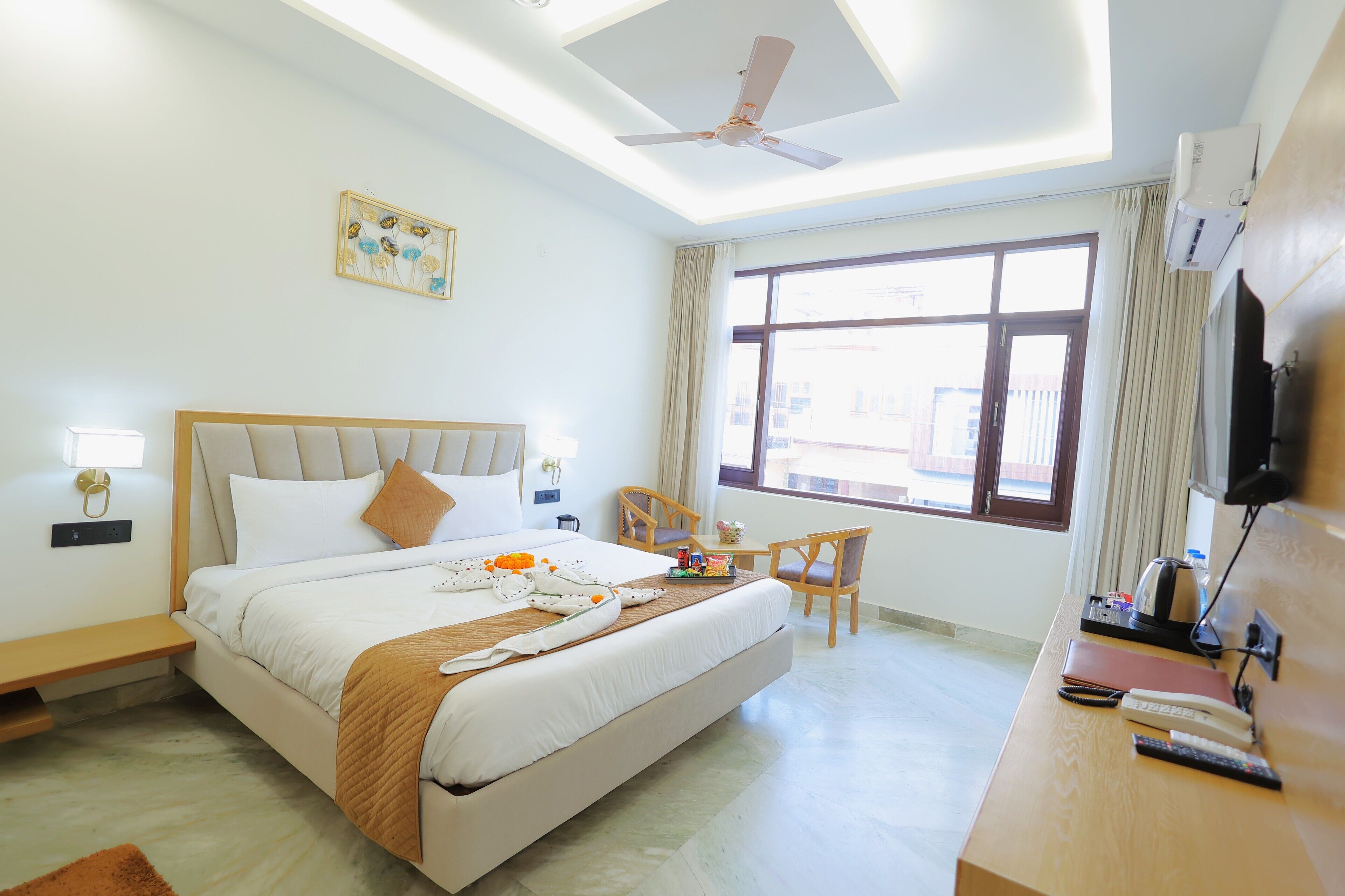 A hotel room with a bed, a desk, a chair, a TV, and a window with curtains.