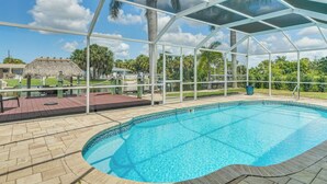 A covered swimming pool with a clear view of the surrounding area, including a thatched-roof structure and palm trees. - 2 Mi to Beach: Canalfront Home in Cape Coral (Cape Coral)