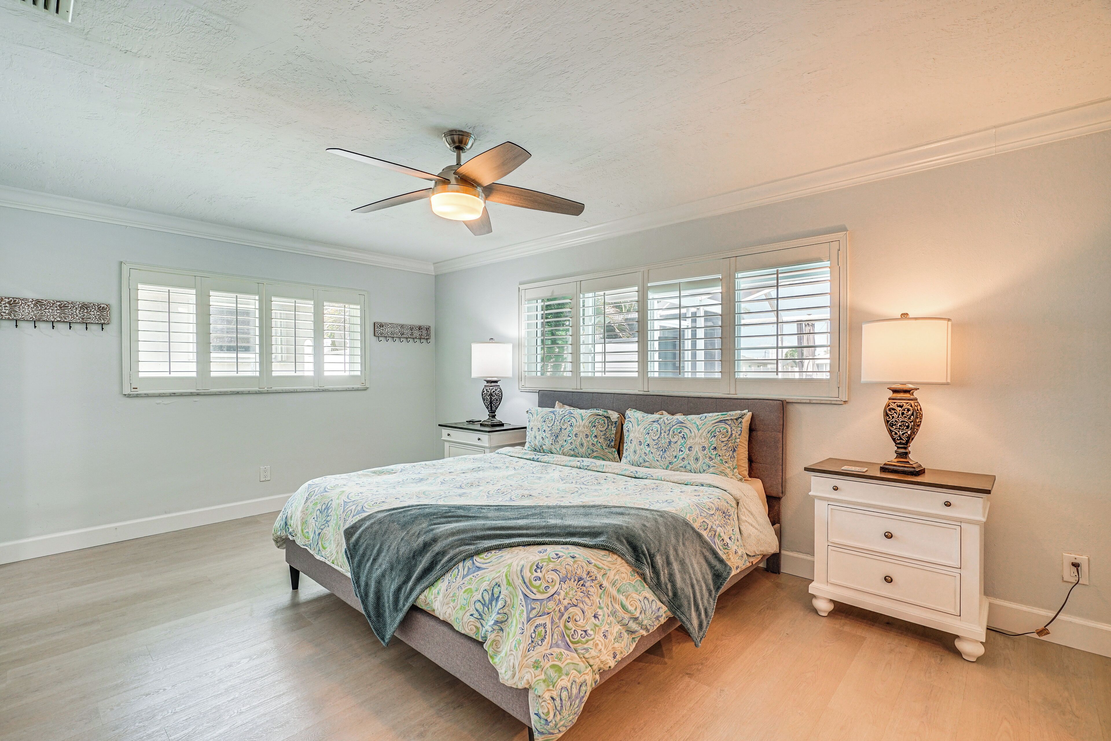 A bedroom with a bed, nightstands, a ceiling fan, and a window with blinds.
