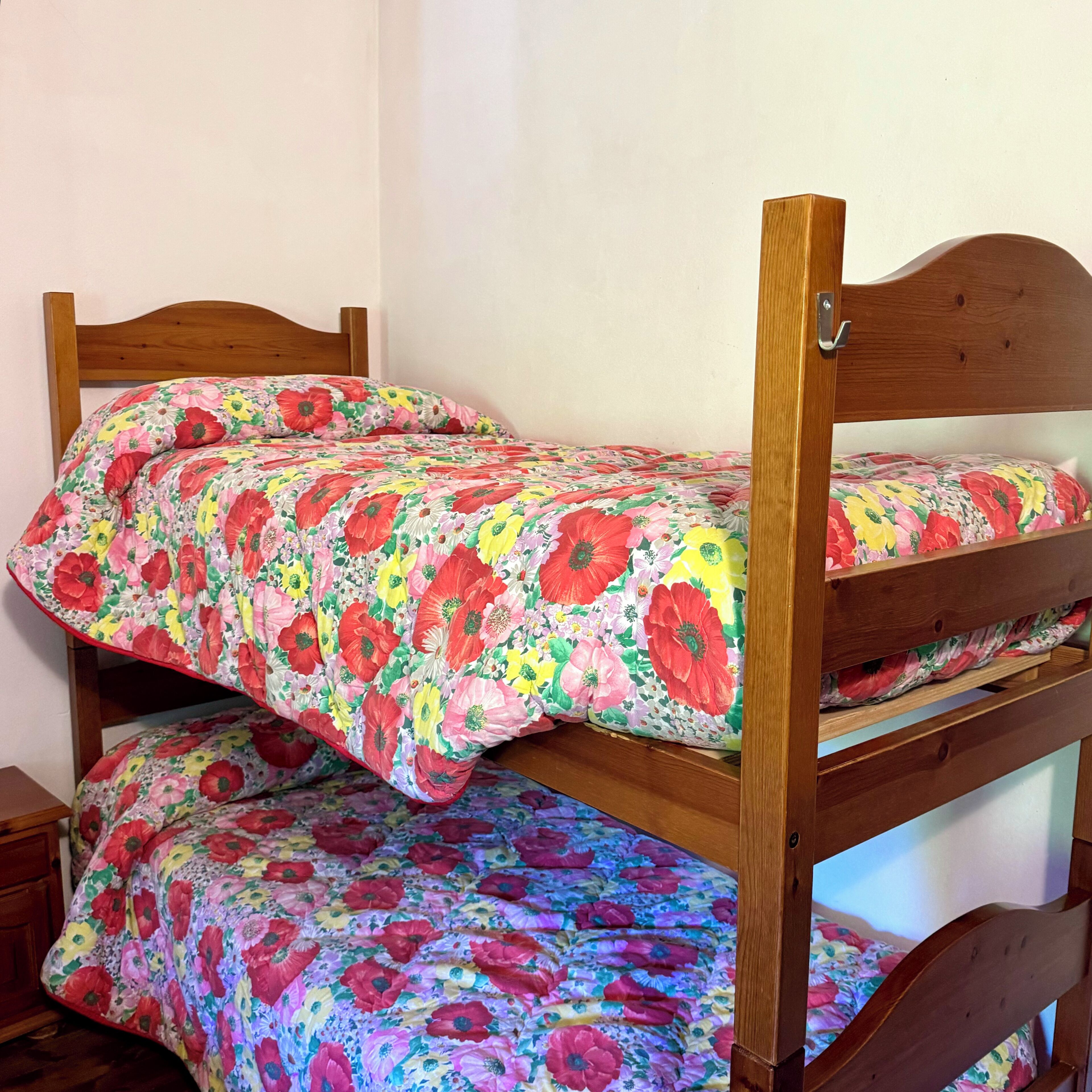 A bunk bed with a floral bedspread and wooden headboard.