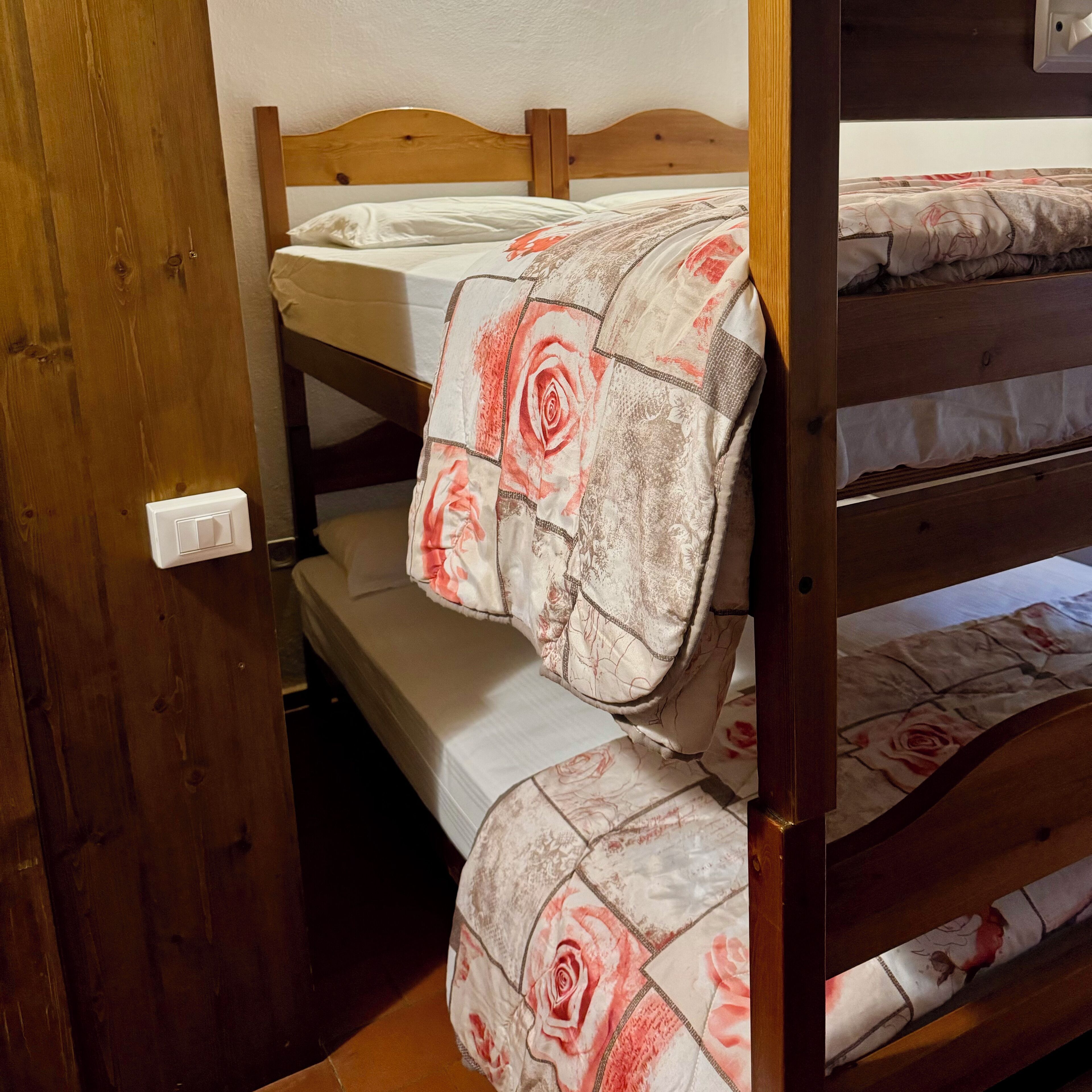 Ein Etagenbett mit einer blumigen Tagesdecke und einem Holz-Kopfstück.