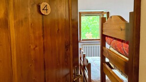 A wooden door with a number '4' sign, leading to a room with a bed and a window. - Albergo Ristorante Ca' di veroli (Bagno di Romagna)