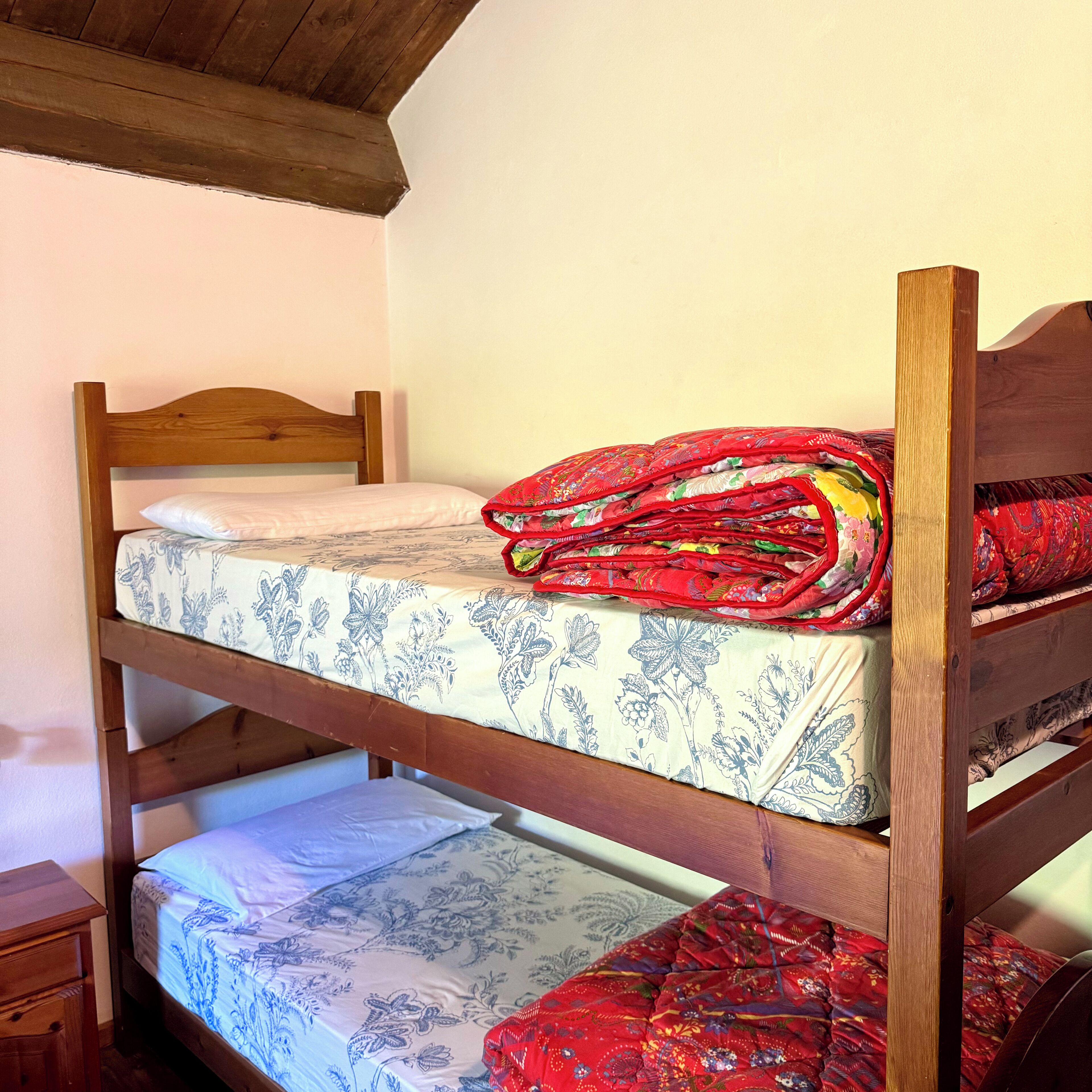 Una cama litera con ropa de cama de estampado floral y cabecera de madera.
