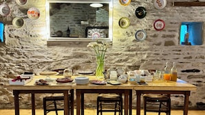 A rustic dining area with a stone wall, a large mirror, and various decorative plates. - Albergo Ristorante Ca' di veroli (Bagno di Romagna)