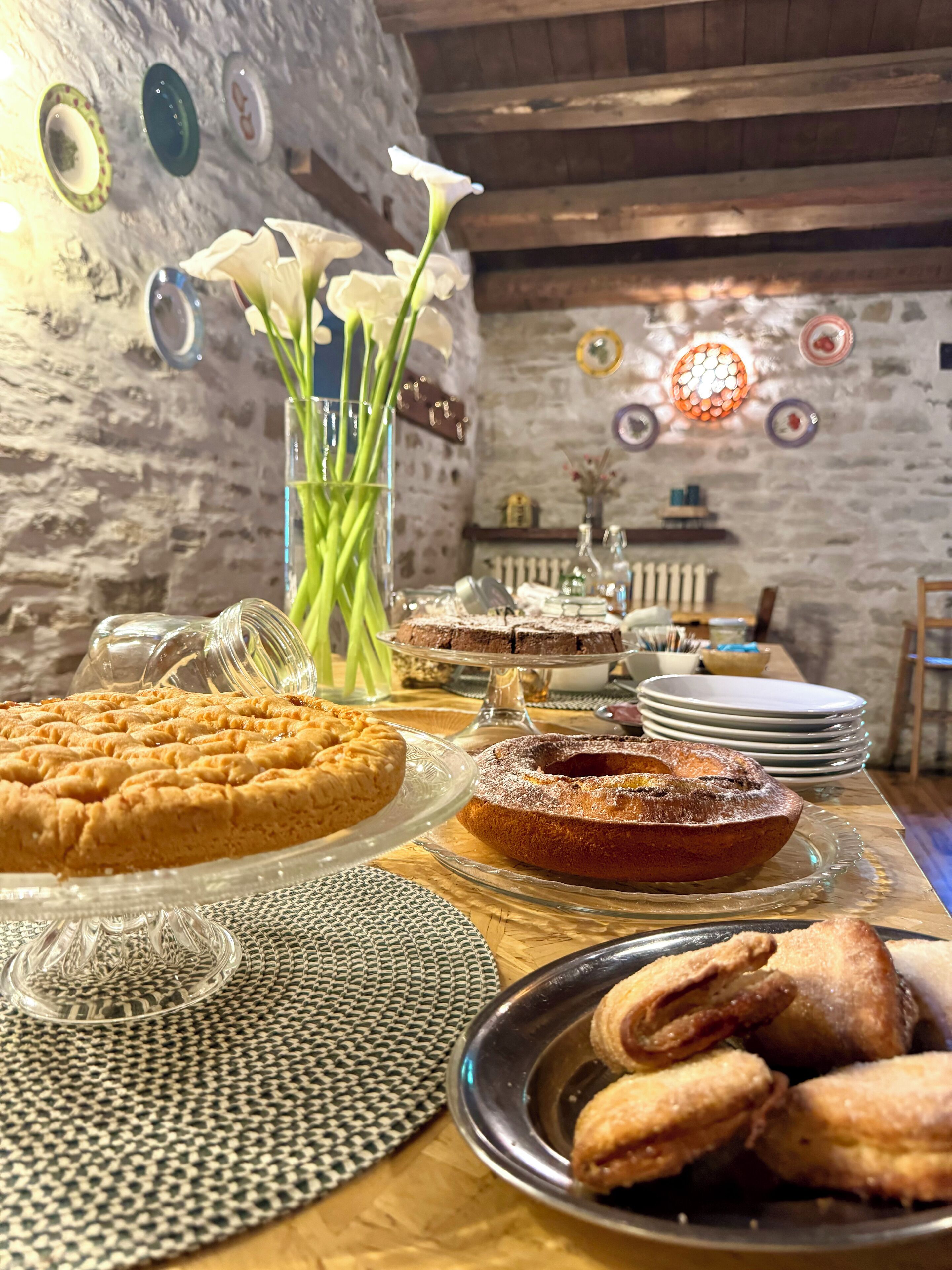 Un tavolo da pranzo con diversi dolci e un vaso di fiori bianchi.