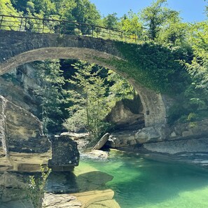 A stone bridge over a clear river with surrounding greenery. - Albergo Ristorante Ca' di veroli (Bagno di Romagna)