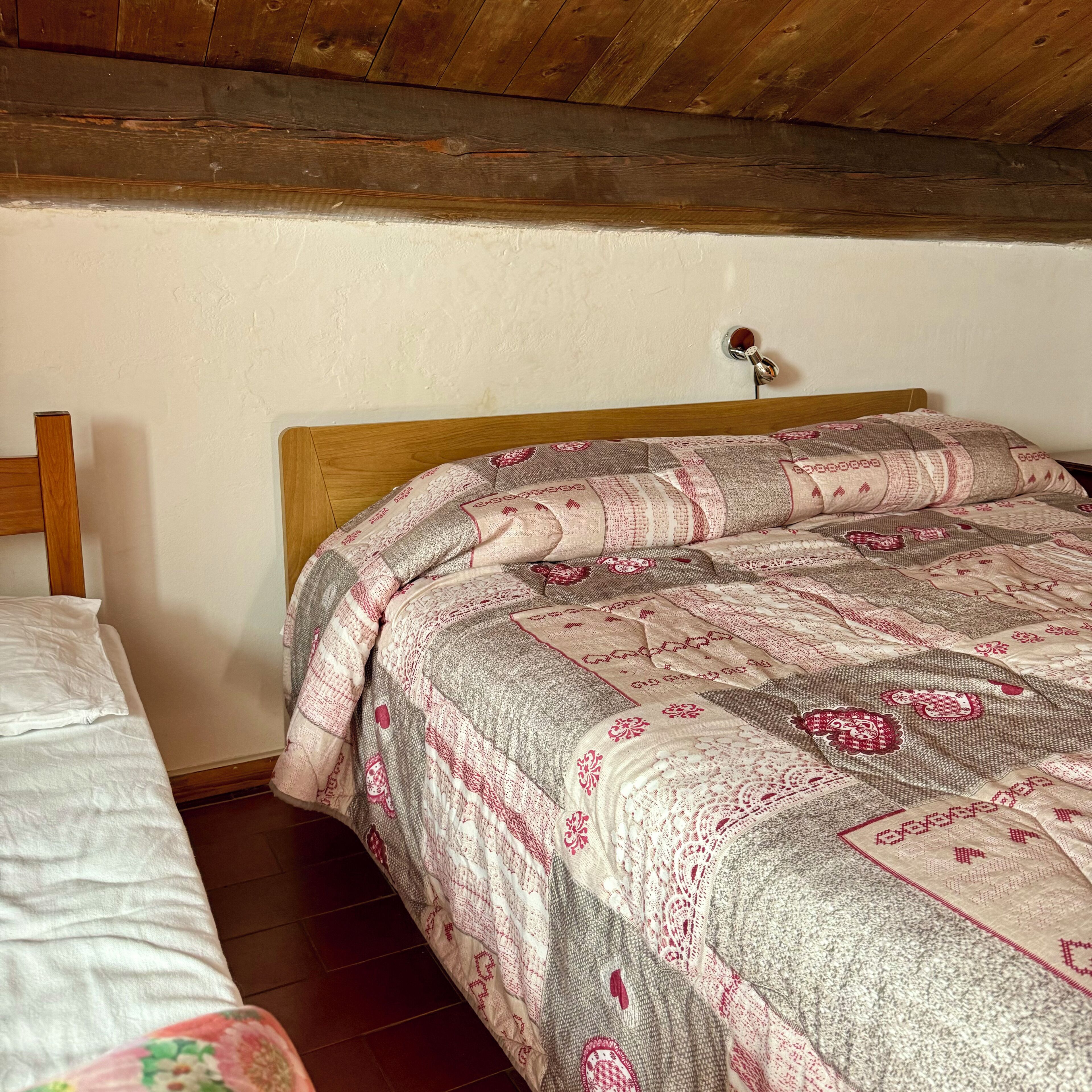 Un dormitorio con cabecera de madera, cama con colcha estampada y edredón blanco.