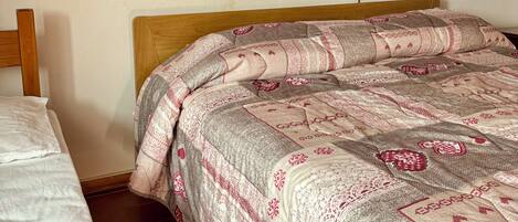 Un dormitorio con cabecera de madera, cama con colcha estampada y edredón blanco.