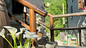 A rustic stone staircase leading to a wooden door, a metal bucket with flowers, and a clear blue sky. - Albergo Ristorante Ca' di veroli (Bagno di Romagna)