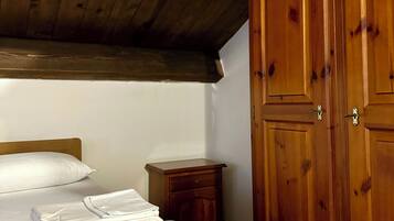 Ein Schlafzimmer mit Holzboden, einem Bett mit floralem Überwurf, einem Nachttisch und einem Holzschrank.