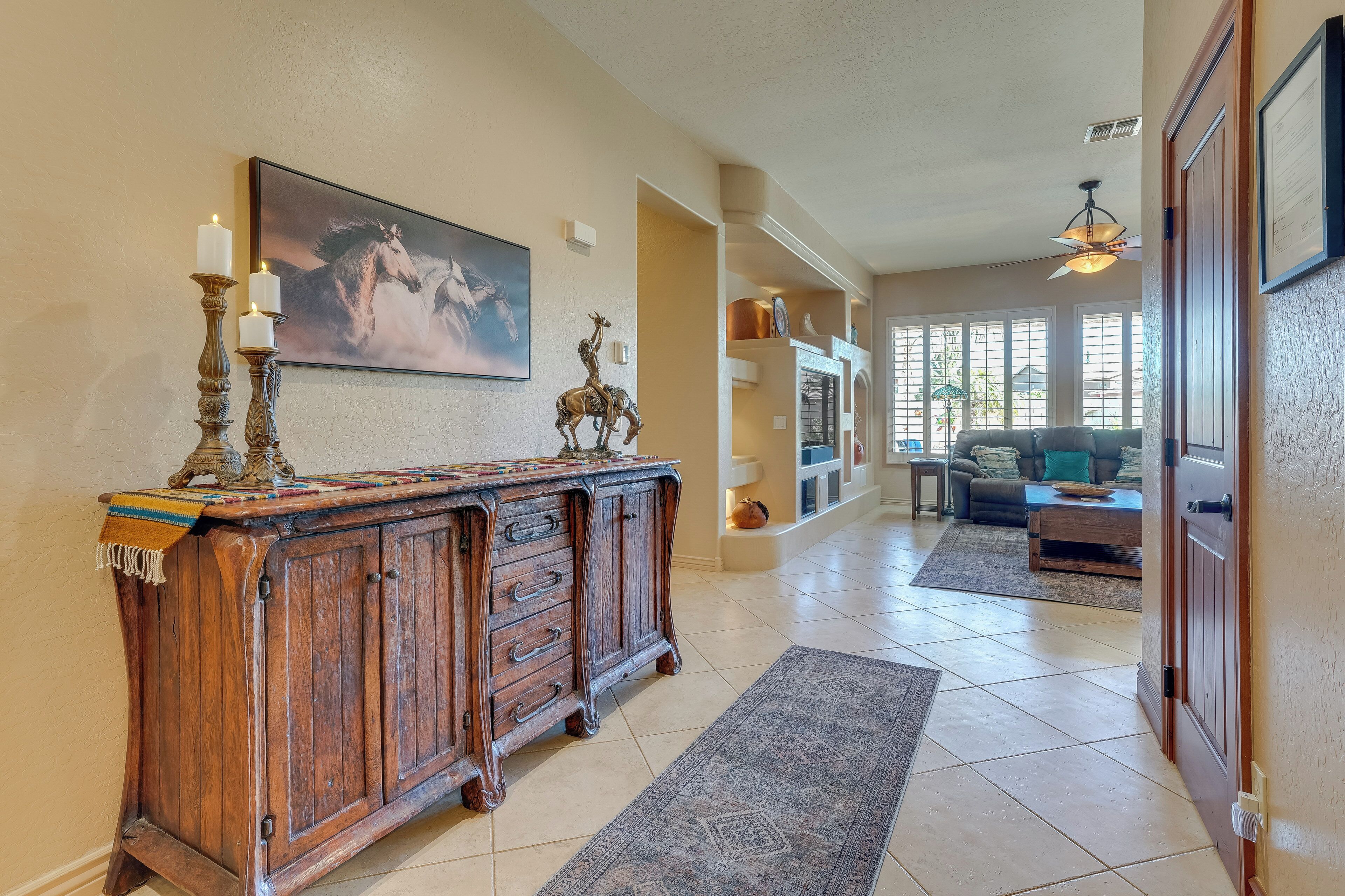 A hallway with a wooden cabinet, a rug, and a painting of a horse.