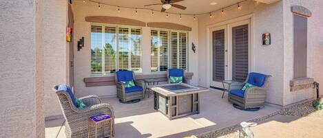 An outdoor patio with wicker furniture, a ceiling fan, and string lights.