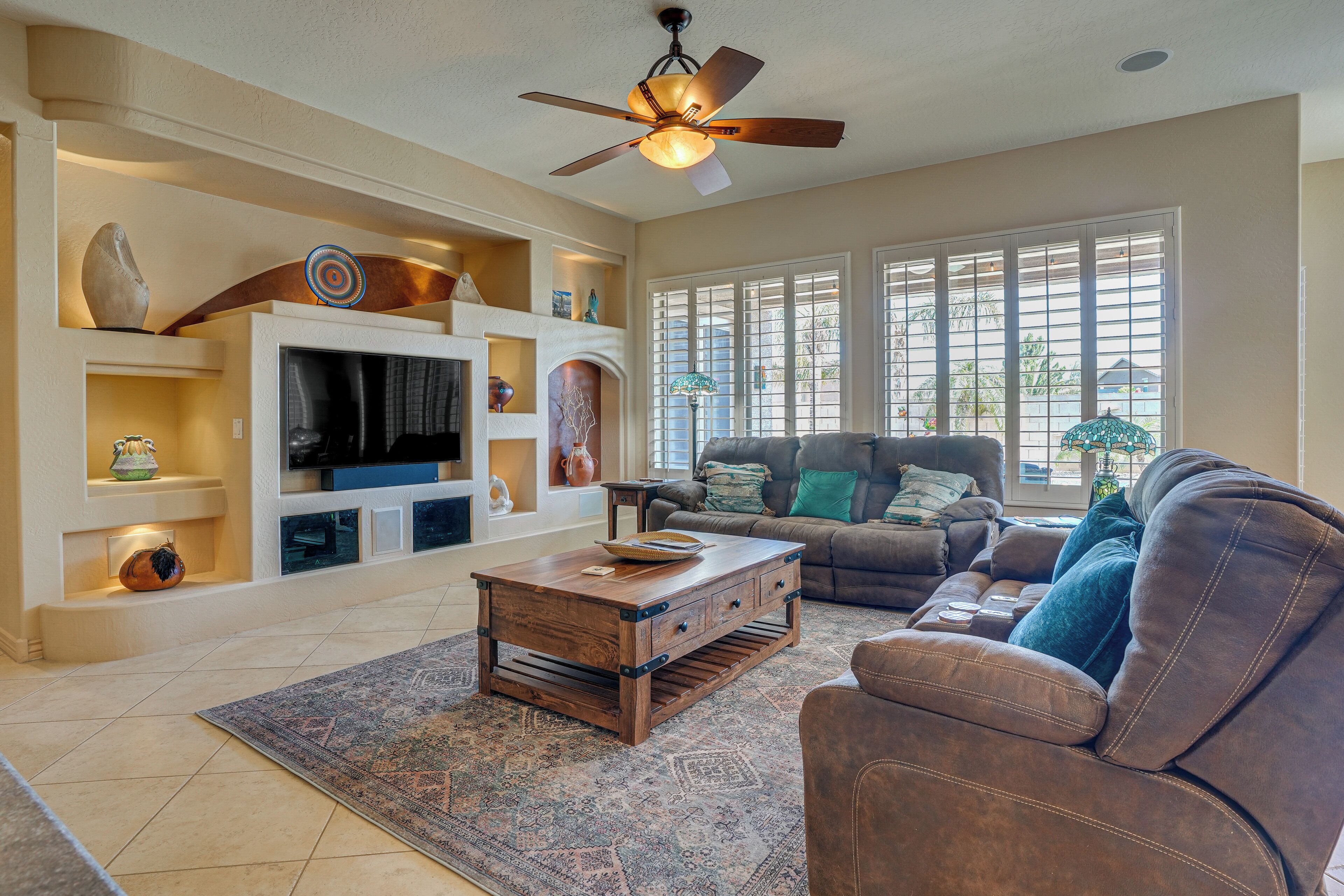 A living room with a fireplace, television, and a ceiling fan.
