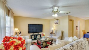 A living room with a flat-screen TV, a ceiling fan, and a floral arrangement. - 7 Mi to Satellite Beach: Melbourne Home w/ Yard (Melbourne)