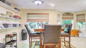 A dining area with a wooden table, two chairs, a ceiling fan, and shelves with storage boxes.