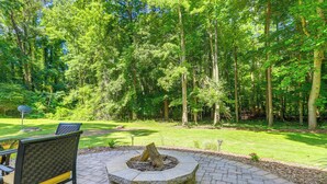 A stone fire pit surrounded by a paved patio area, with a chair and a table visible to the left. - Cozy Jonesboro Studio w/ Patio ~ 22 Mi to Atlanta! (Jonesboro)