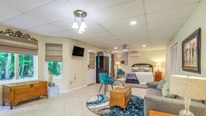 A spacious living room with a large window, a sofa, a coffee table, and a television on the wall. - Cozy Jonesboro Studio w/ Patio ~ 22 Mi to Atlanta! (Jonesboro)