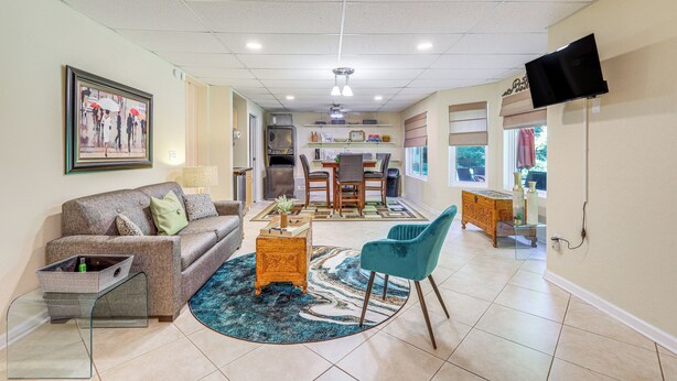 A spacious living area with a sofa, coffee table, and a blue chair. There is a dining area with a table and chairs, and a kitchen in the background. - Cozy Jonesboro Studio w/ Patio ~ 22 Mi to Atlanta! (Jonesboro)