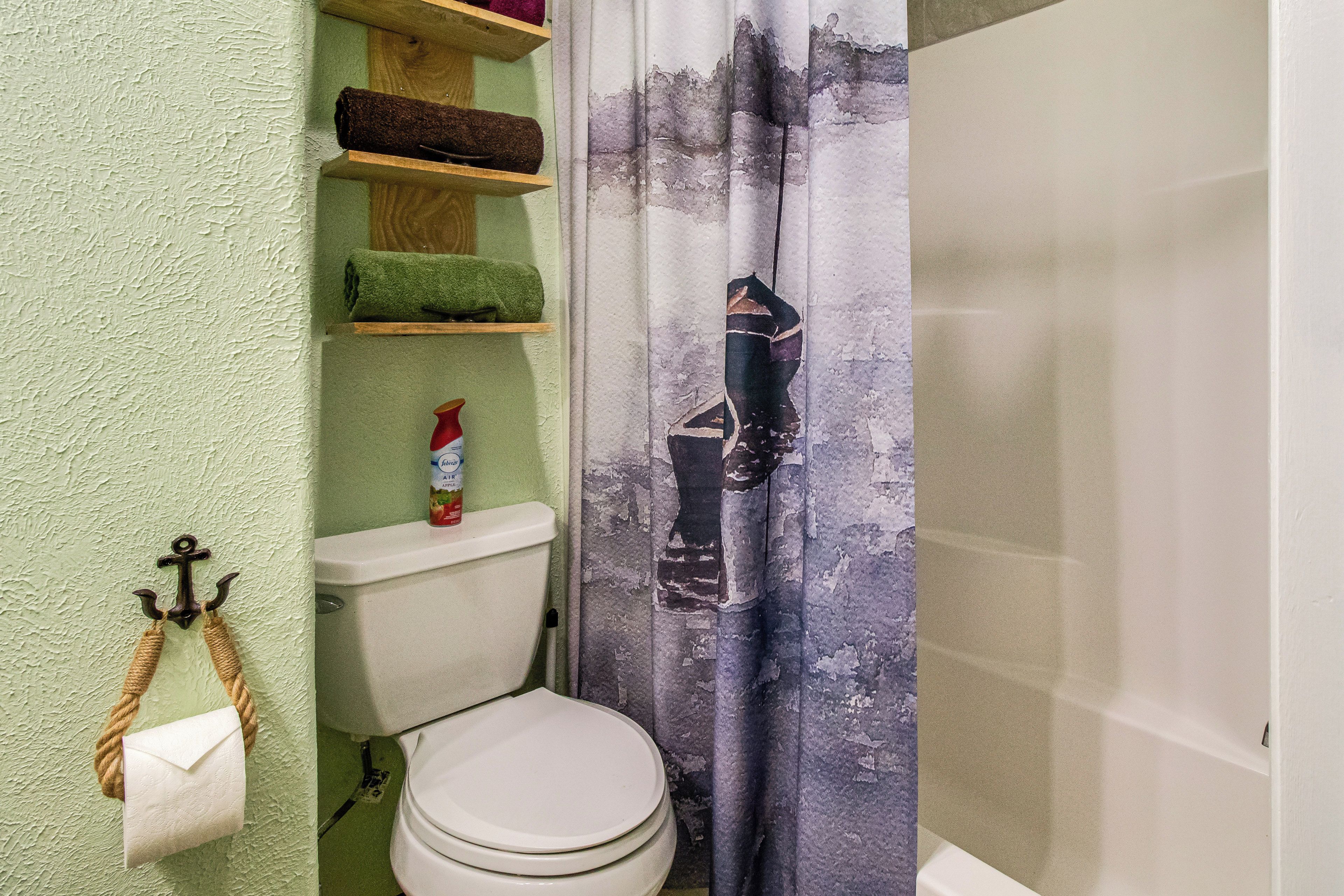 A bathroom with a toilet, a shelf with towels, and a shower curtain.